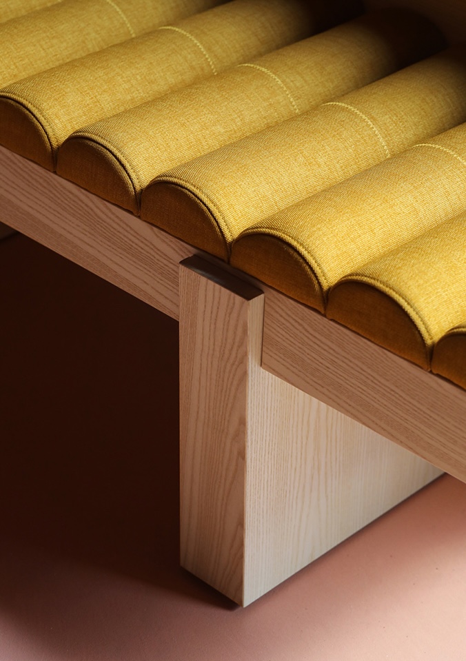 Detail of yellow upholstered bench with oak frame