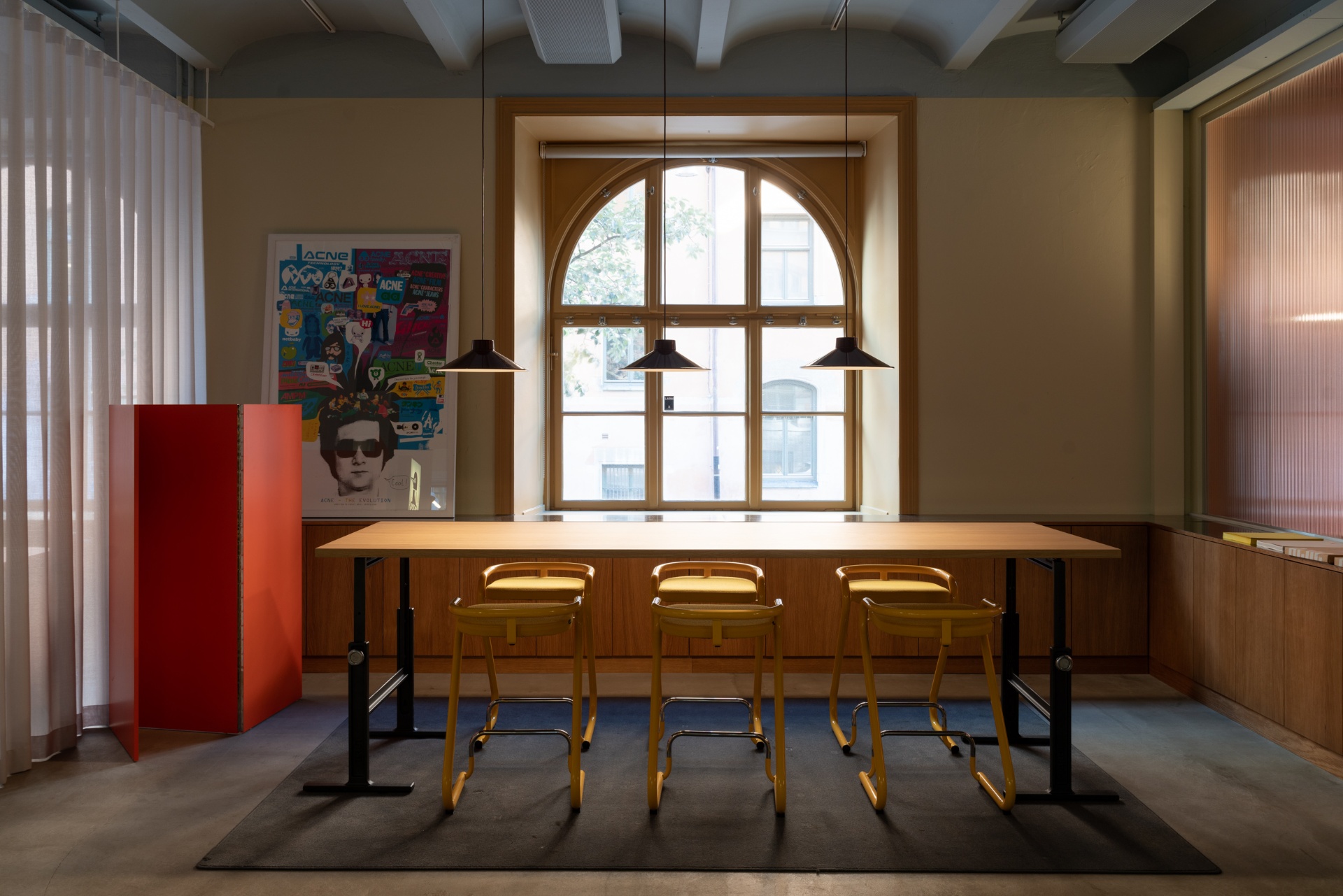 Meeting table beneath an arched window at Acne Advertising