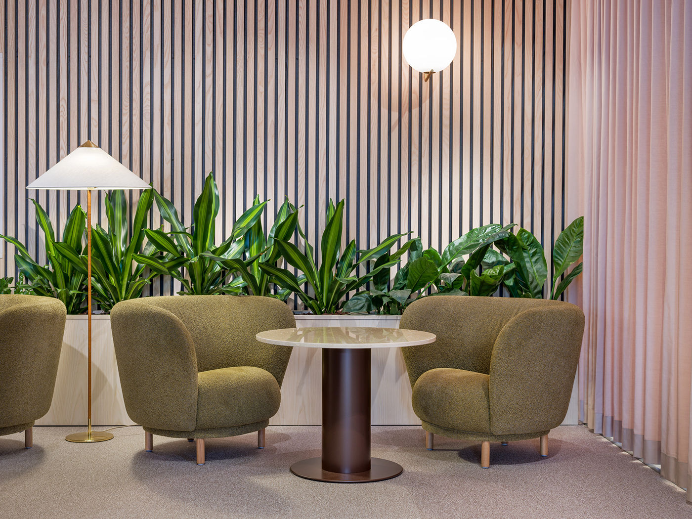 Seating nook with green armchairs and planted backdrop