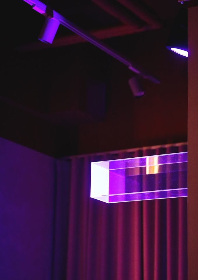 Purple-lit interior with velvet curtain and glass display